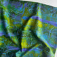 Draped abstract fabric in moss green, chartreuse, and purple with fine light blue splatters and linework.