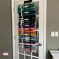 Vinyl organizer hanging on a wooden door, featuring numerous horizontal pockets filled with rolled vinyl in various colors and prints