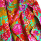Kaffe Fassett Collective February 2026 Collection. Vibrant, draped floral fabric featuring large pink, orange, and purple flowers on a bright mint green background.