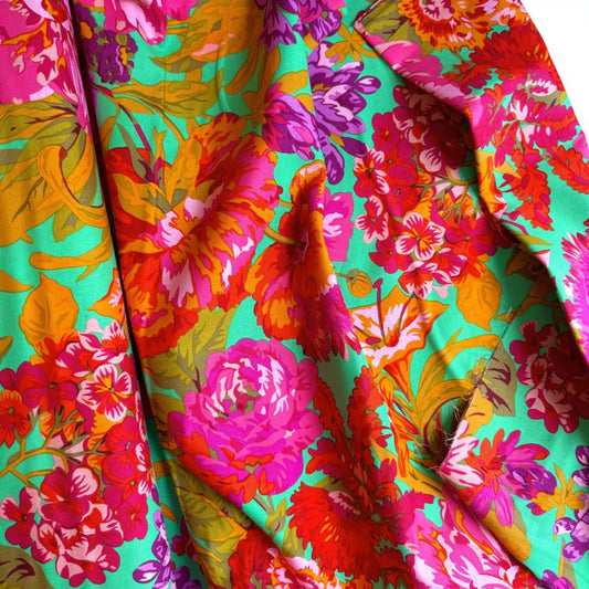 Kaffe Fassett Collective February 2026 Collection. Vibrant, draped floral fabric featuring large pink, orange, and purple flowers on a bright mint green background.