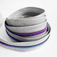 Stack of gray silver zipper tape with purple and blue teeth on a white background