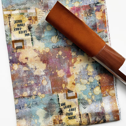 Abstract watercolor collage fabric in blue, mauve, tan and yellow with artistic paint splatters, geometric patterns and vintage-inspired text