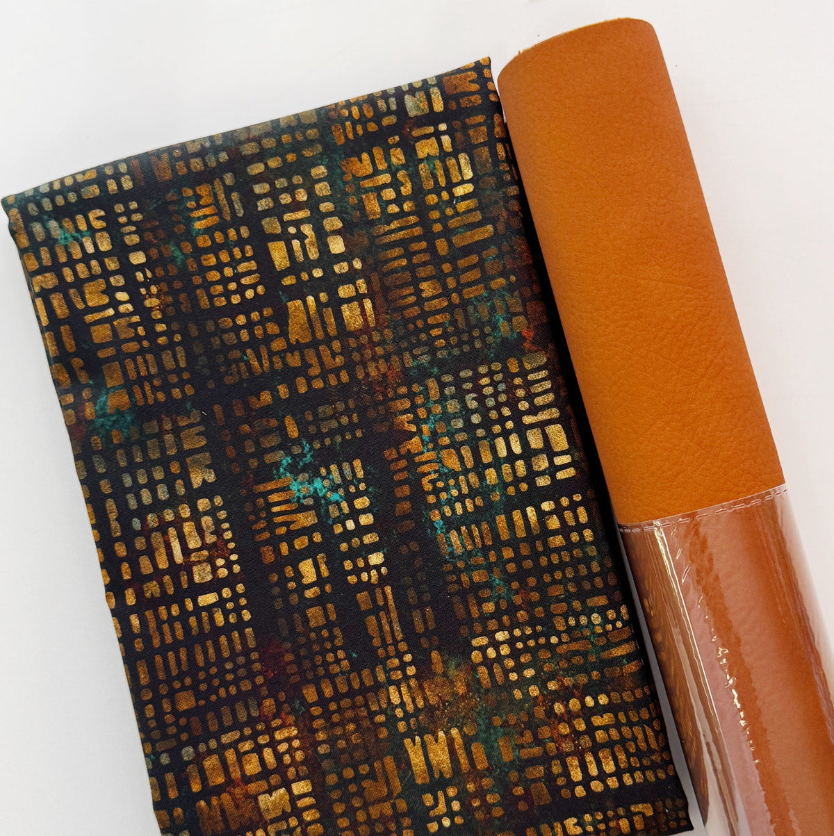 A roll of brown vegan leather and a folded yard of e Moda Tranquil Patina Luminary Stack in Earth 48116 13