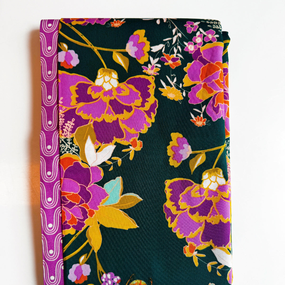 Art Gallery Fabrics two-piece fabric bundle featuring a dark teal quilting cotton with large, vibrant purple, magenta, and orange floral prints, paired with a coordinating magenta geometric wavy border fabric