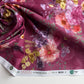 Floral fabric with pink and yellow flowers on a red background, displayed on a white surface.