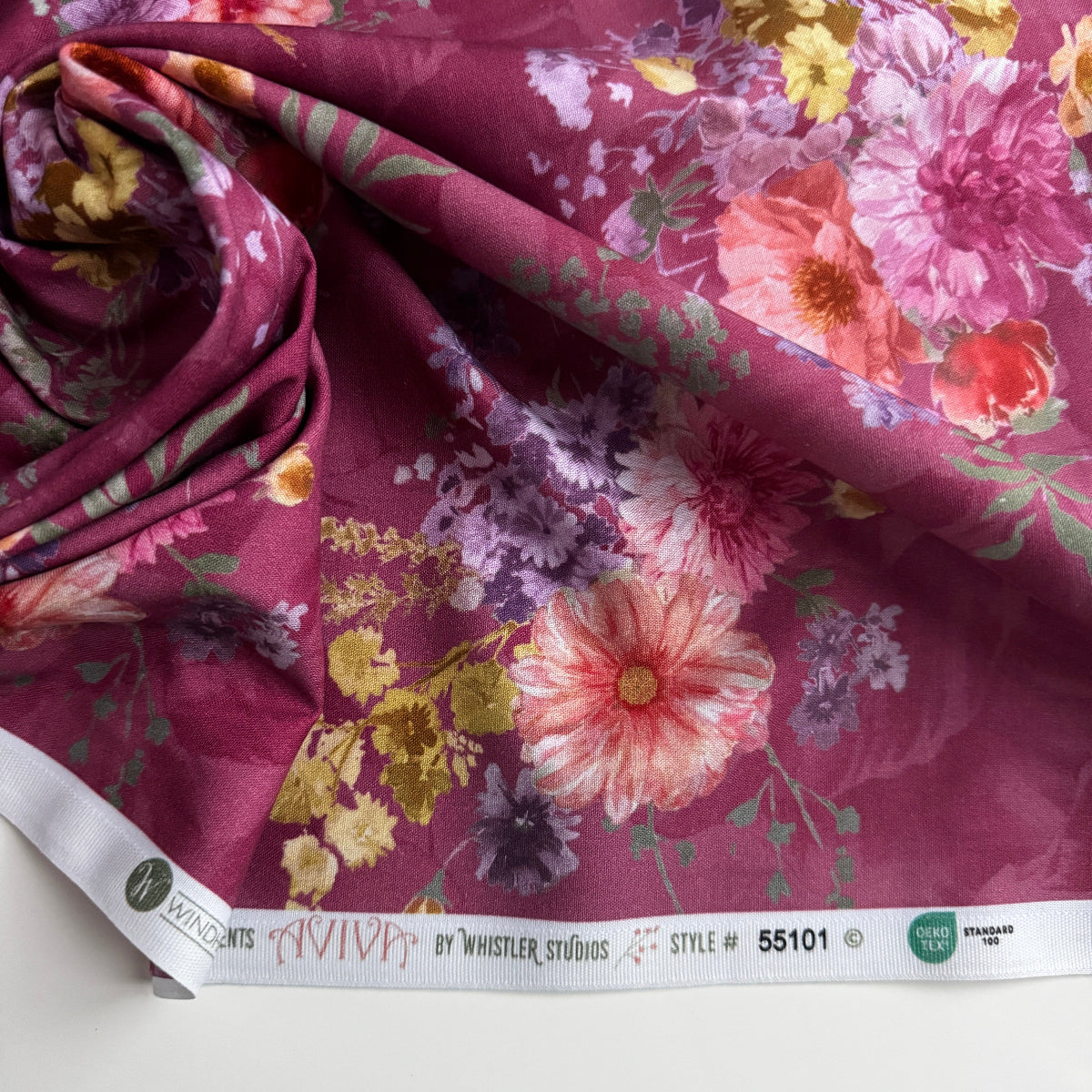 Floral fabric with pink and yellow flowers on a red background, displayed on a white surface.