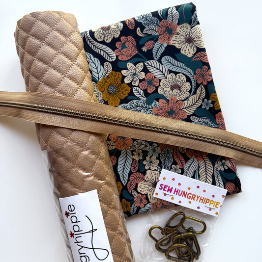 A sewing kit laid out on a white background, including a rolled tan quilted fabric piece, a dark floral fabric panel, a tan zipper, metal clips, and a small branded tag reading 'Sem Hungry Hippie'.