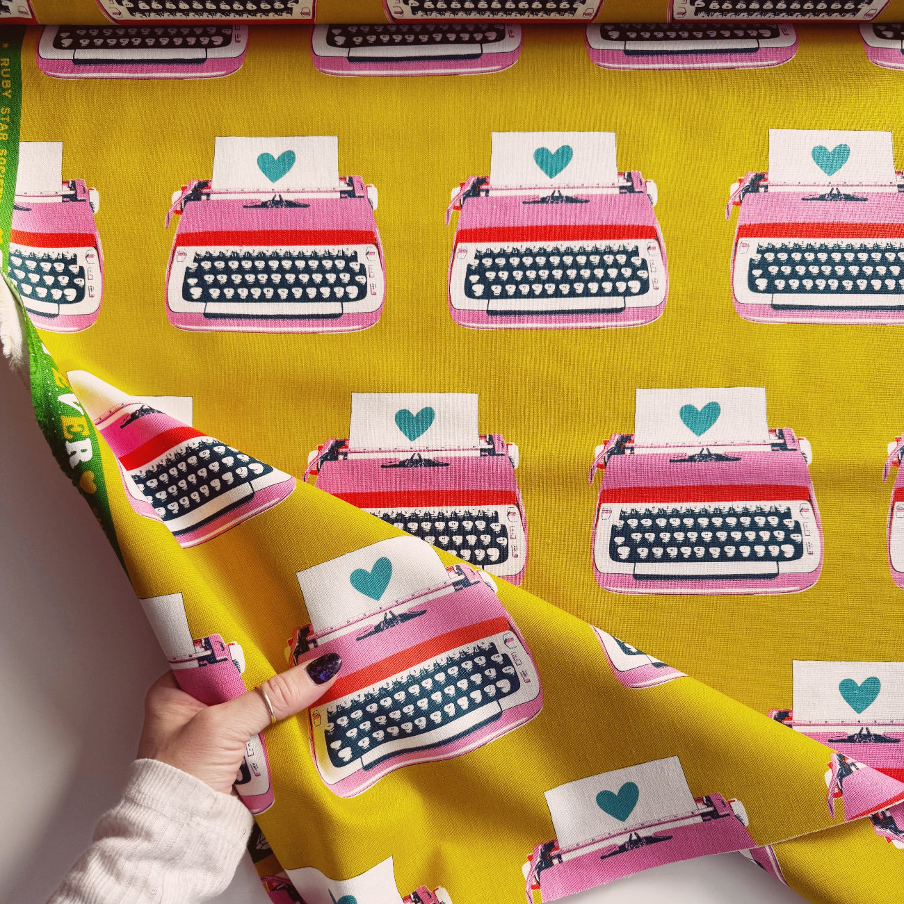 Pink typewriter-shapedmotifs with hearts on a yellow background canvas fabric