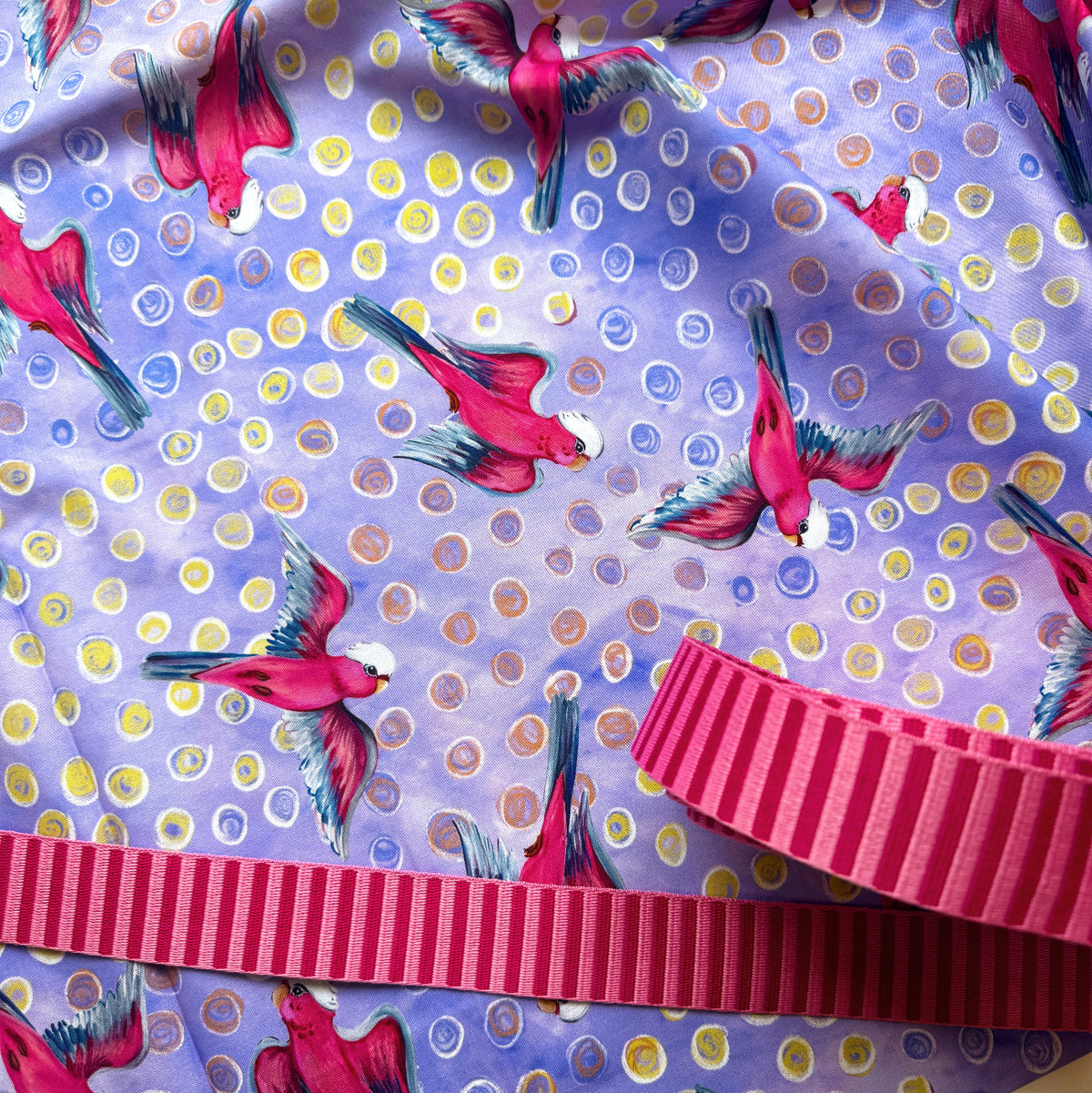 Birds of a Feather Galahs fabric in lavender by Helen Godden for FreeSpirit Fabrics, featuring vibrant pink galahs in flight with colorful textured polka dots