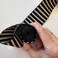 A hand holding a rolled bundle of classic black and white horizontally striped jacquard woven webbing strap for bag making