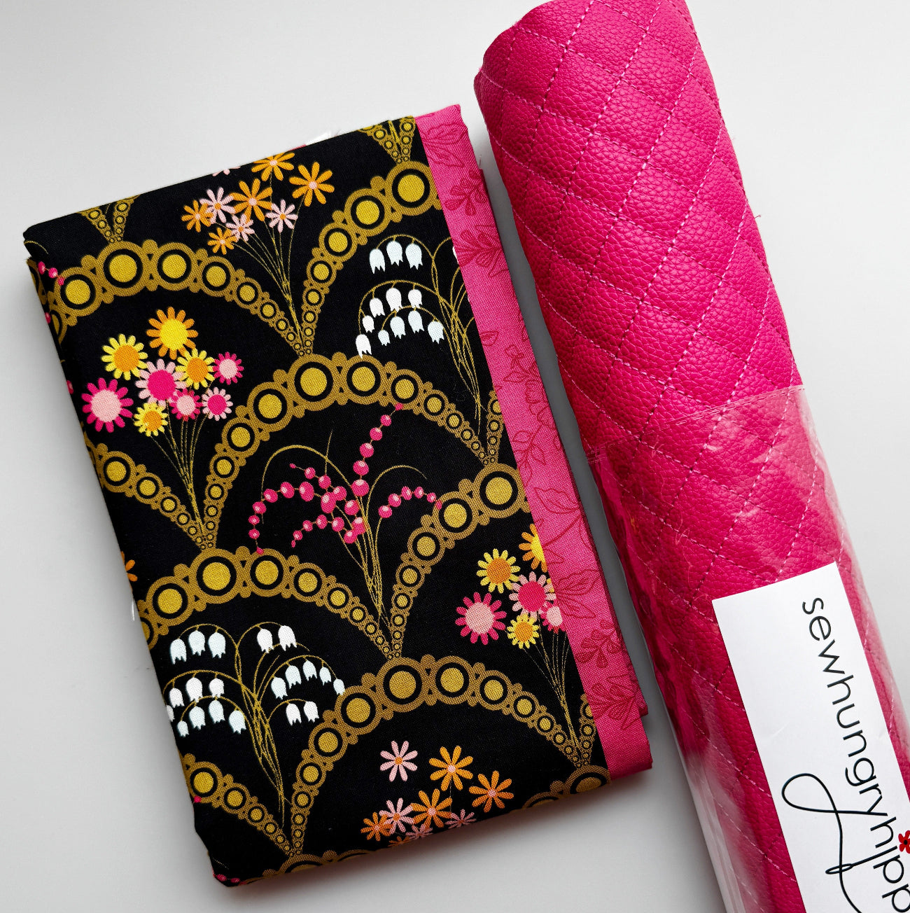 Black floral sewing fabric with gold accents and pink flowers paired with pink quilted pebbled vinyl.