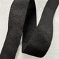 A close-up view of a premium black jacquard woven webbing strap showing a subtle, raised diamond geometric texture on a light gray background 9D44D092