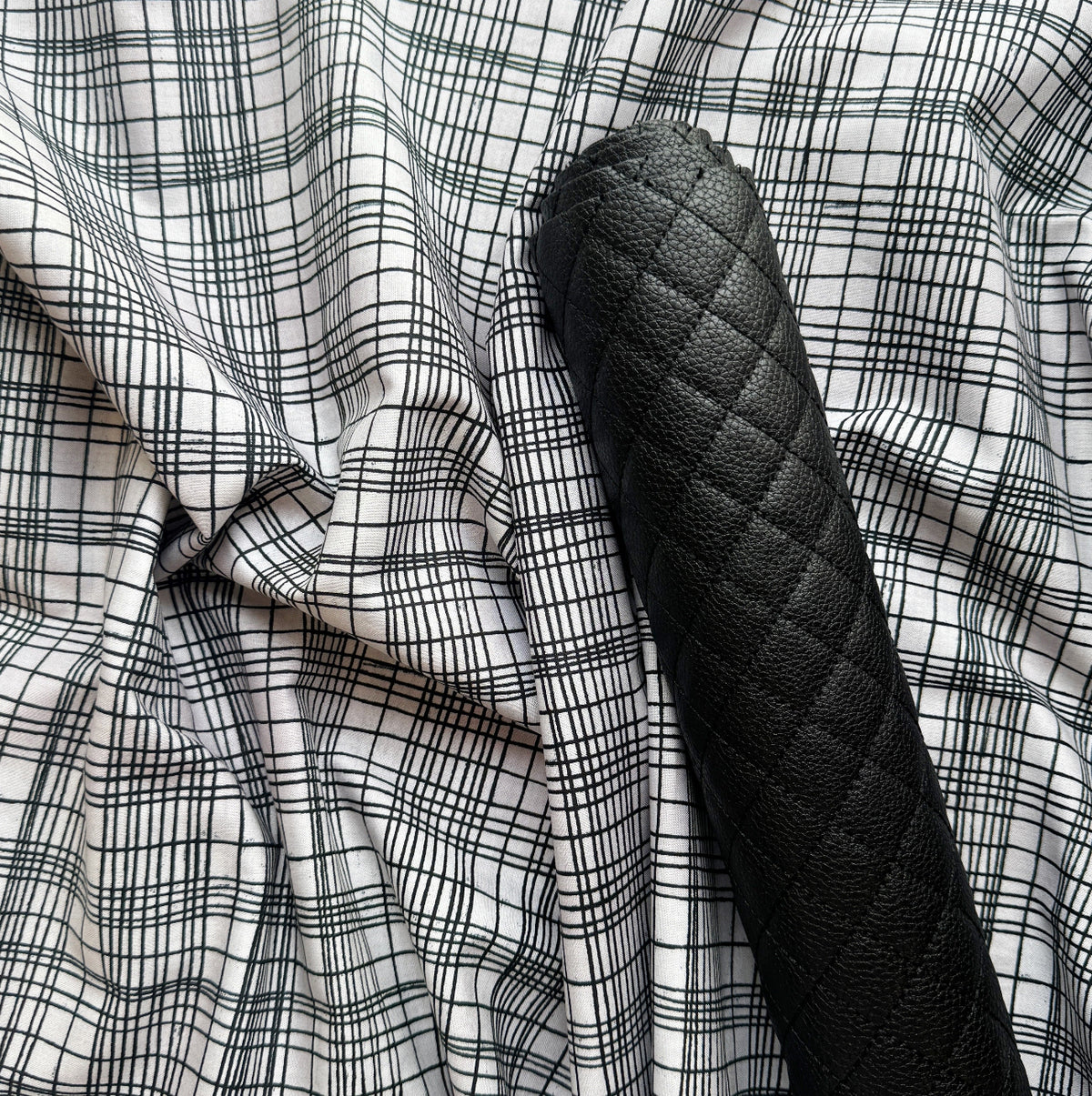White fabric with black grid pattern paired with black diamond-quilted faux leather for bag making