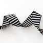 A clean studio shot of wavy, textured black and white striped jacquard woven webbing strap on a solid white background