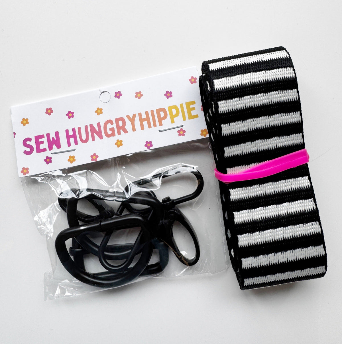 Sew Hungry Hippie DIY bag-making kit featuring black-and-white striped seatbelt webbing alongside a package of black hardware.