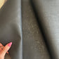 Black cork textured fabric with a hand holding it