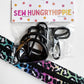 A packaged set of black plastic zipper pulls and a colorful leopard-print zipper tape strip. The items are sealed in a clear plastic bag with a white header card printed with the brand name 'SEW HUNGRY HIPPIE' and small pink and orange flowers.