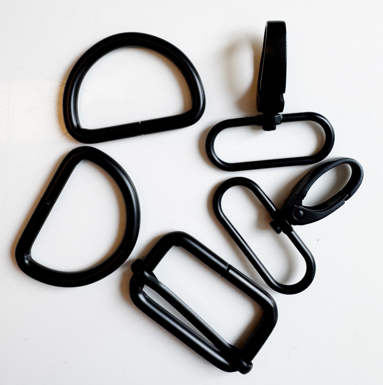 Six black metal carabiner-style hardware pieces arranged on a plain white background.