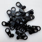 A pile of small black zipper pull tabs or zipper teeth components on a plain white background.