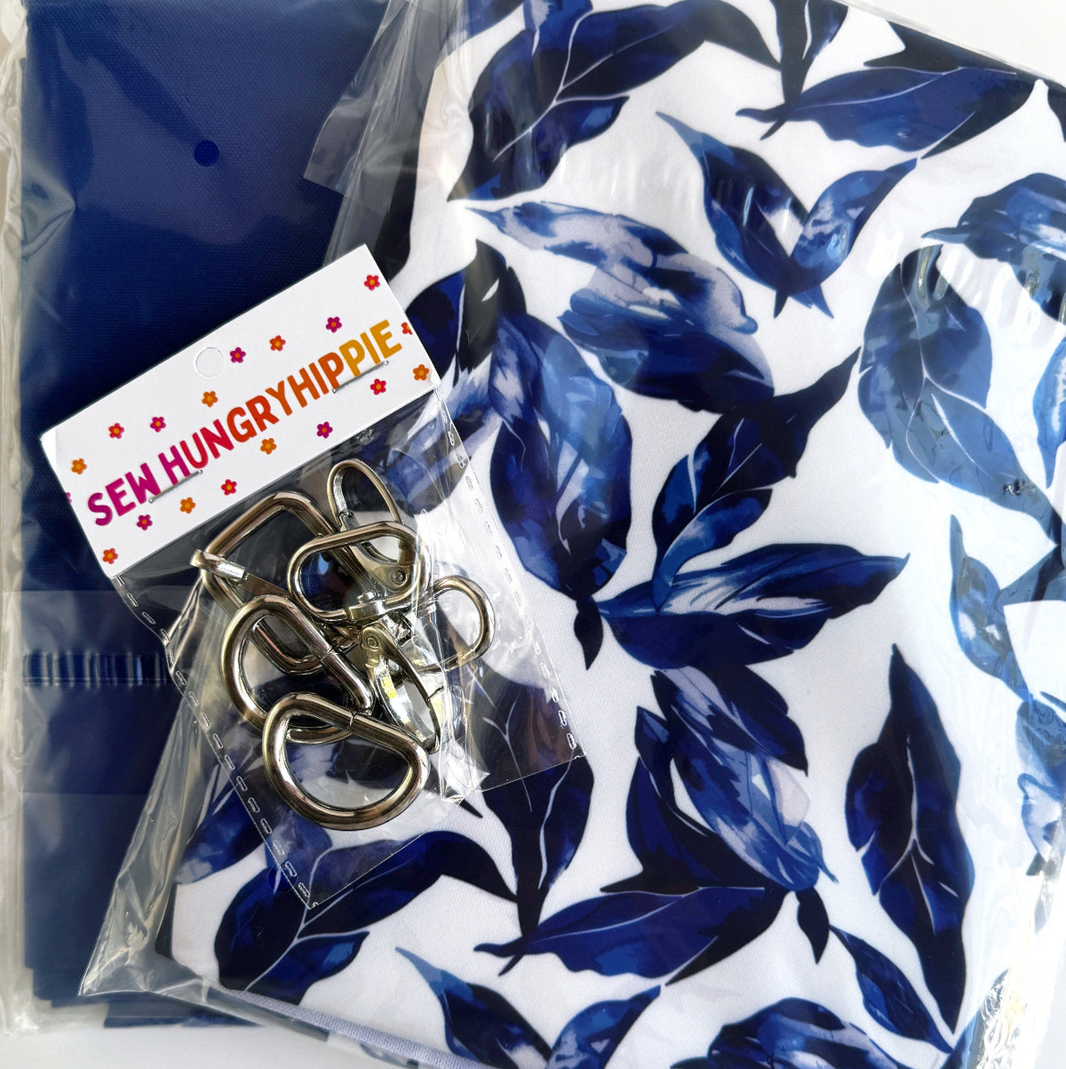 Bag-making kit featuring the Blue Leaves Watercolor Bonded Nylon Fabric from Sew HungryHippie, with matching silver hardware.