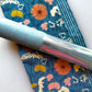 Blue floral fabric featuring colorful flowers and a coordinating light blue sewing tool.
