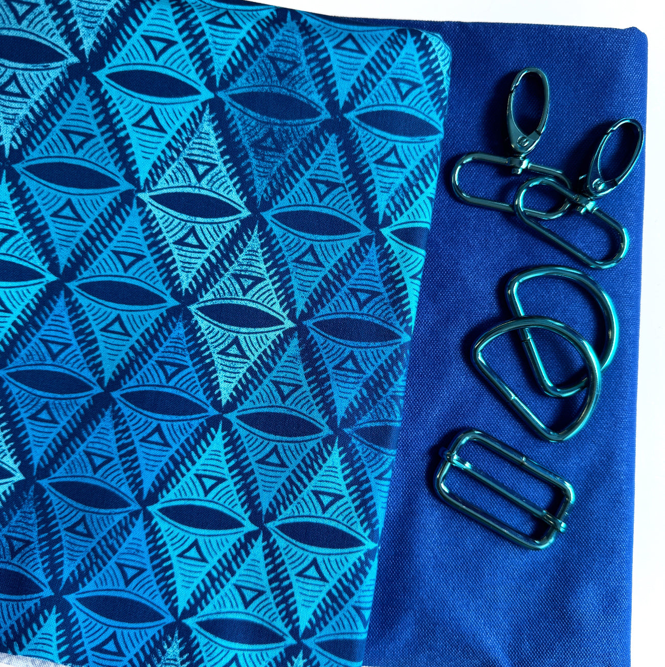 Blue geometric cotton fabric paired with coordinating blue canvas and teal metallic bag hardware for sewing handbags, crossbody bags, totes, and handmade accessories.