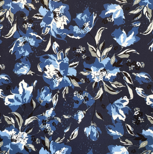 A close-up of a floral fabric pattern featuring blue, light blue, and white flowers with gray leaves on a dark navy background.