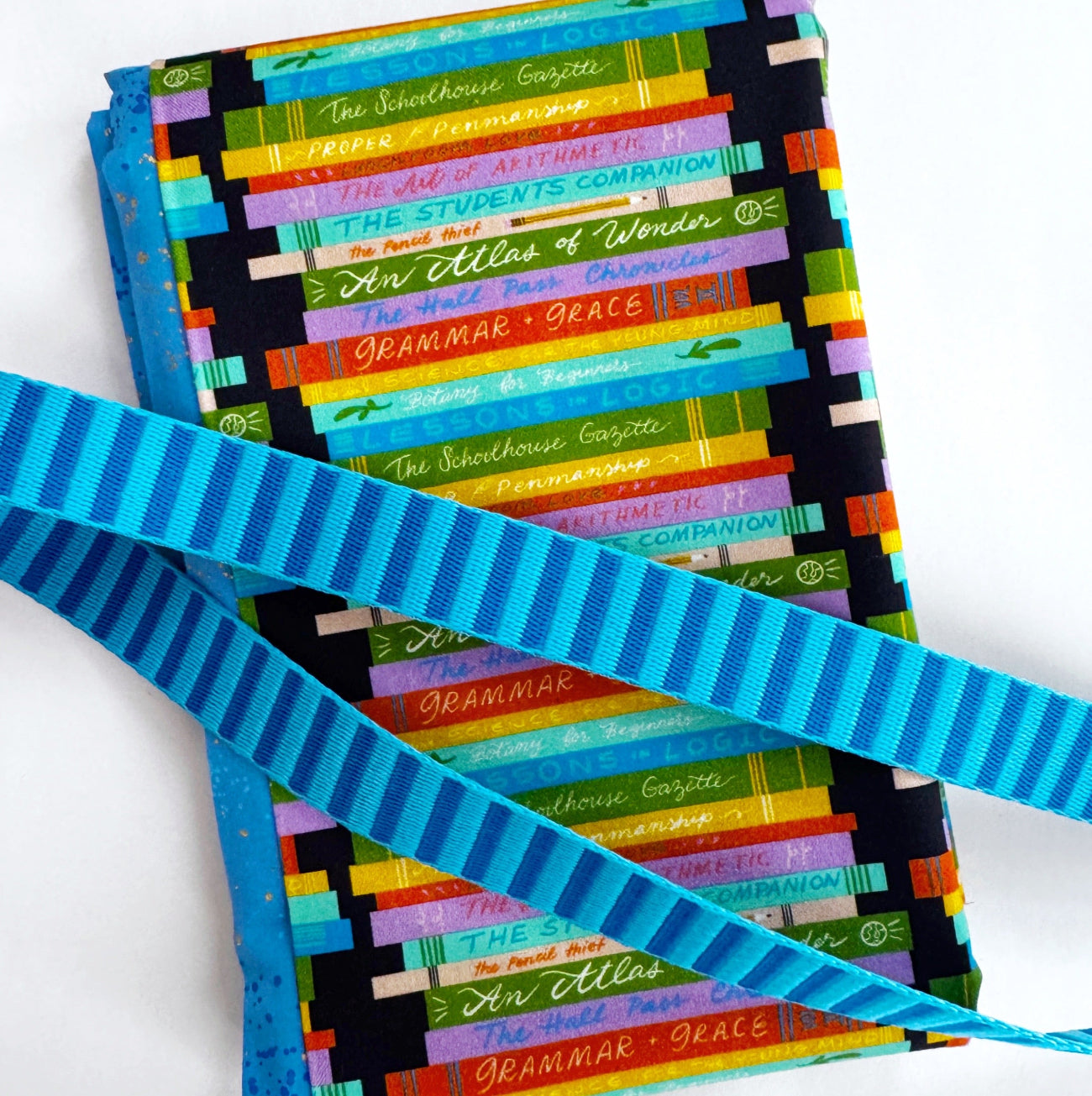 2-yard fabric bundle featuring colorful book print cotton fabric paired with Ruby Star Society Speckled fabric and 3 yards of blue striped webbing for sewing handbags, totes, backpacks, and handmade accessories.