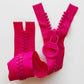Chunky bright pink molded plastic zipper with large interlocking teeth, matching circular ring pull, and wide fabric tape