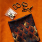 Brown textured faux leather with dark leaf print fabric and gold-tone bag hardware arranged for a sewing project.