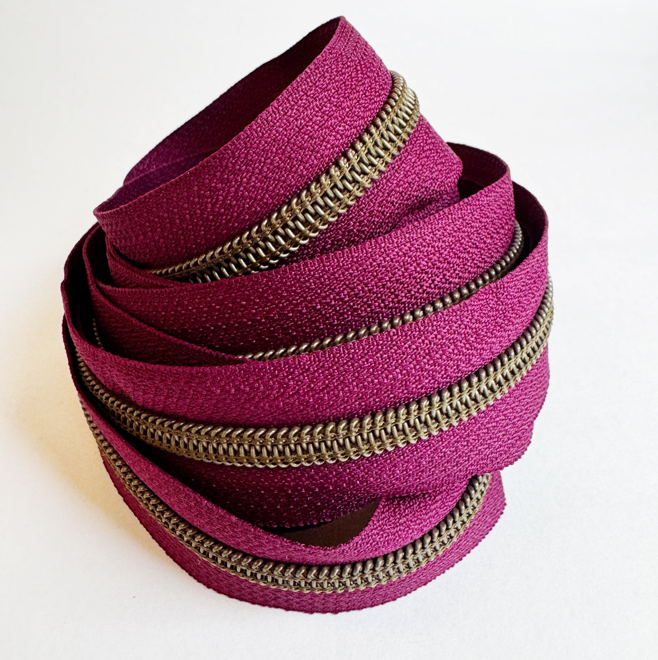 3-yard cut of #5 burgundy nylon zipper tape with antique brass teeth for handbag, purse, wallet, and bag making sewing projects.