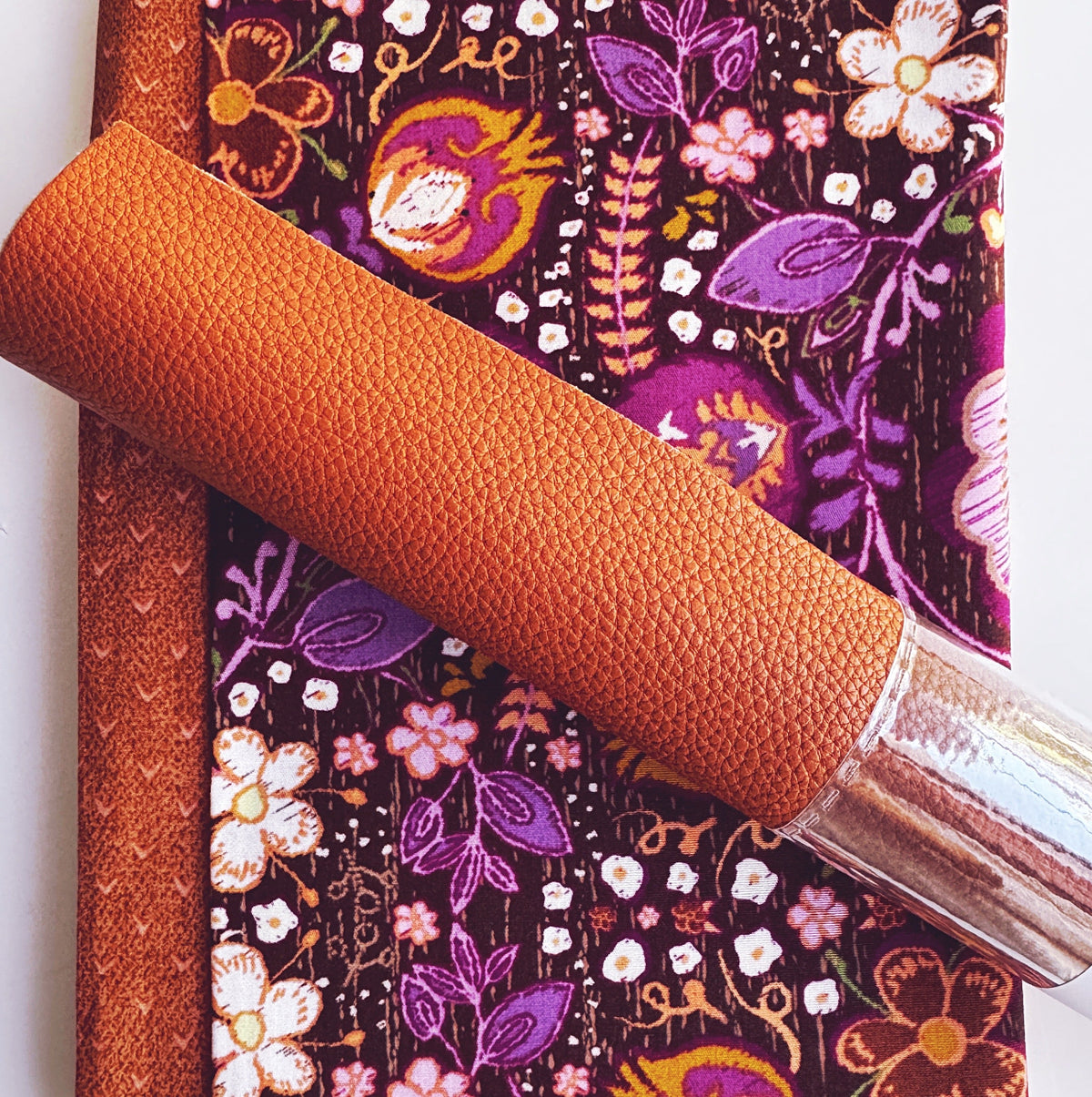 Rust orange textured vinyl and purple floral fabric for a colorful handmade bag-making project