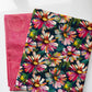 Two folded fabric pieces on a white background: one dark navy floral textile with large pink, white, yellow, and green flowers, and one pink textile with a circular dot pattern.