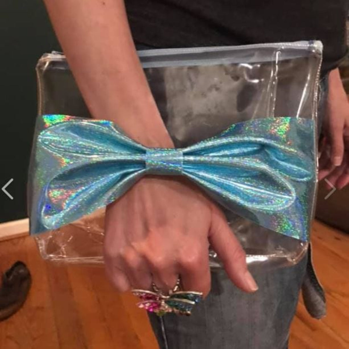 Woman holding a clear clutch with a blue bow.
