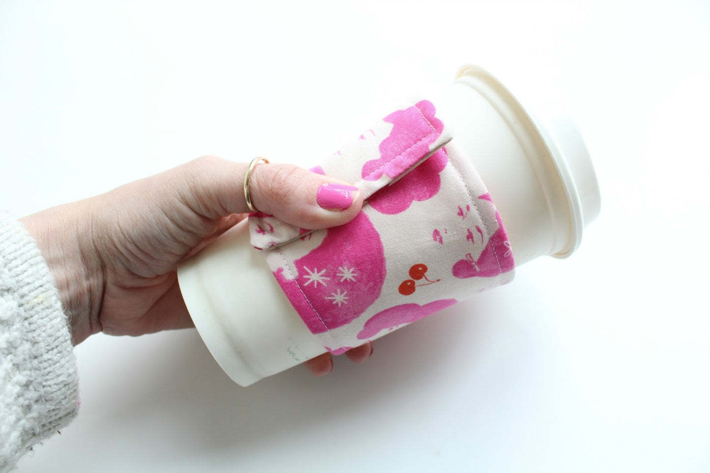 Hand holding coffee cup with pink sleeve tutorial.
