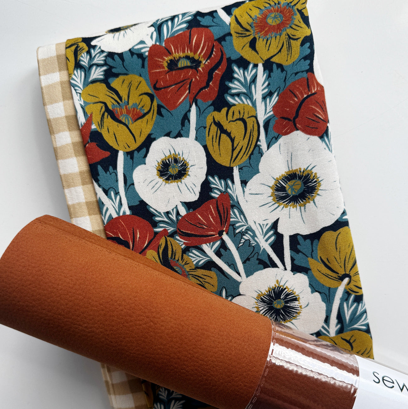 Cognac faux suede paired with coordinating wildflower floral cotton fabric and beige gingham cotton fabric, perfect for handbags, totes, backpacks, wallets, and sewing projects.