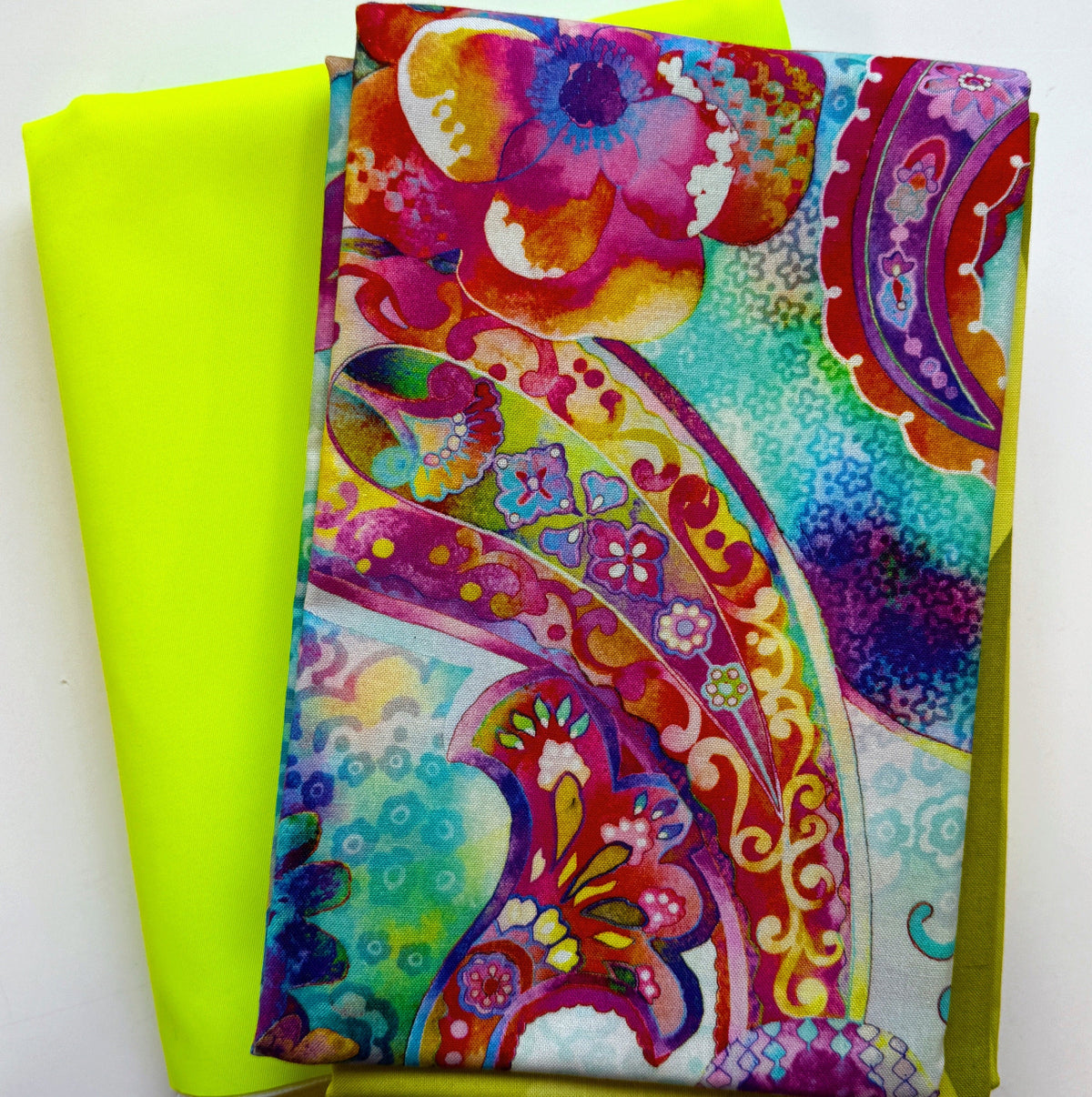Colorful watercolor paisley print fabric paired with solid neon lime-yellow fabric for quilting and bag making