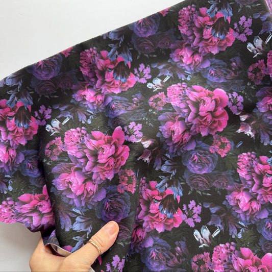 Floral fabric with pink and purple flowers on a dark background, held by a hand.