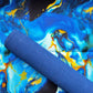 A rolled-up blue textured yoga mat placed diagonally over a vibrant abstract fluid art fabric background with blue, yellow, and black marbling.