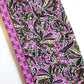 Two folded cotton fabric features a vibrant magenta and green botanical pattern on a white background
