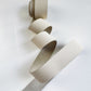 Coiled 1-inch wide cream-colored leather strap for purse and bag handles on a white background.
