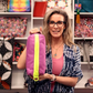 Woman holding an oversized pouch with a chunky neon yellow zipper and matching loop handle