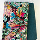 A coordinated fabric destash bundle featuring two neatly folded textiles against a white background. On the left is a vibrant denim fabric measuring 36 by 58 inches, printed with a dense, colorful tropical botanical pattern of leaves and abstract florals in shades of pink, teal, green, orange, and yellow on a black background. Peeking out from underneath on the right is a one-yard piece of textured, solid dark teal coordinating fabric with a woven, linen-like appearance.
