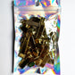 A clear holographic zip pouch containing multiple gold-toned metal hair claw clips, photographed against a plain white background.