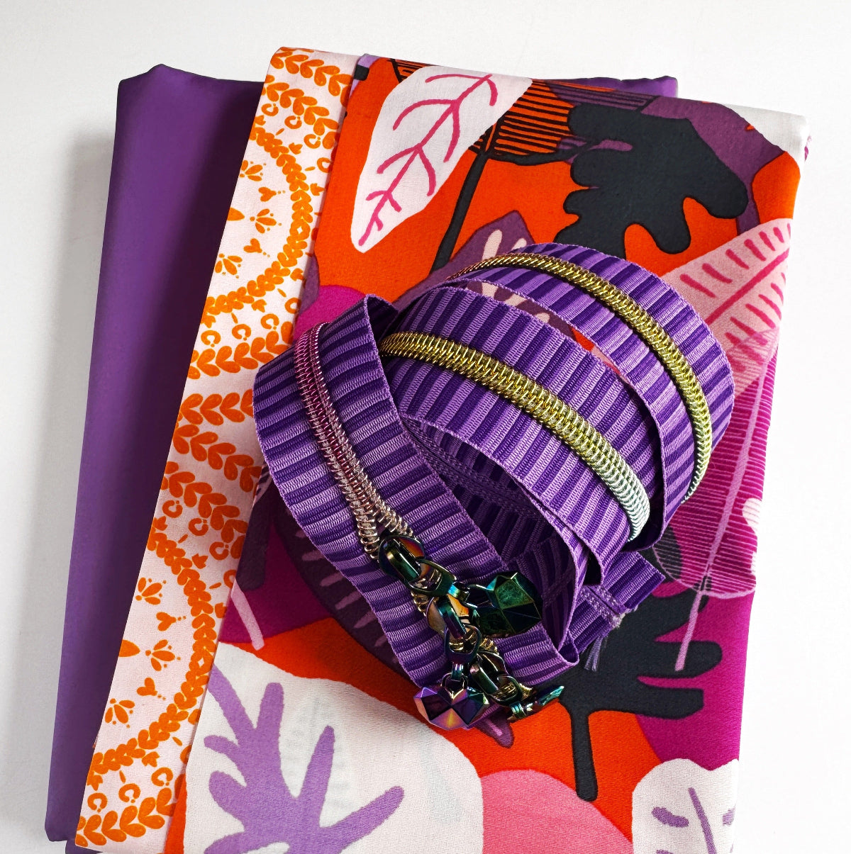 Purple fabric with decorative zippers on a colorful patterned background