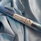Sewing needle with a visible brand label on a light blue fabric background