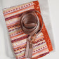 Patterned pouch with a gold zipper and strap on a white background