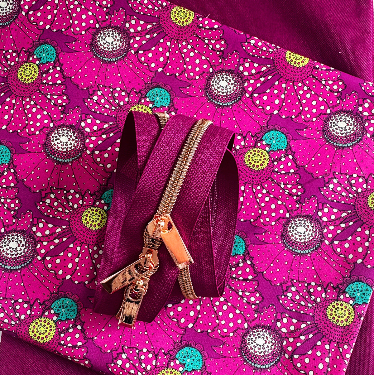 Pink zipper with gold pull on a pink floral fabric background