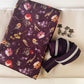 Flat-lay product view of a bag-making kit with floral cotton fabric, cream bonded nylon lining, plum zipper tape, and decorative flower pulls.