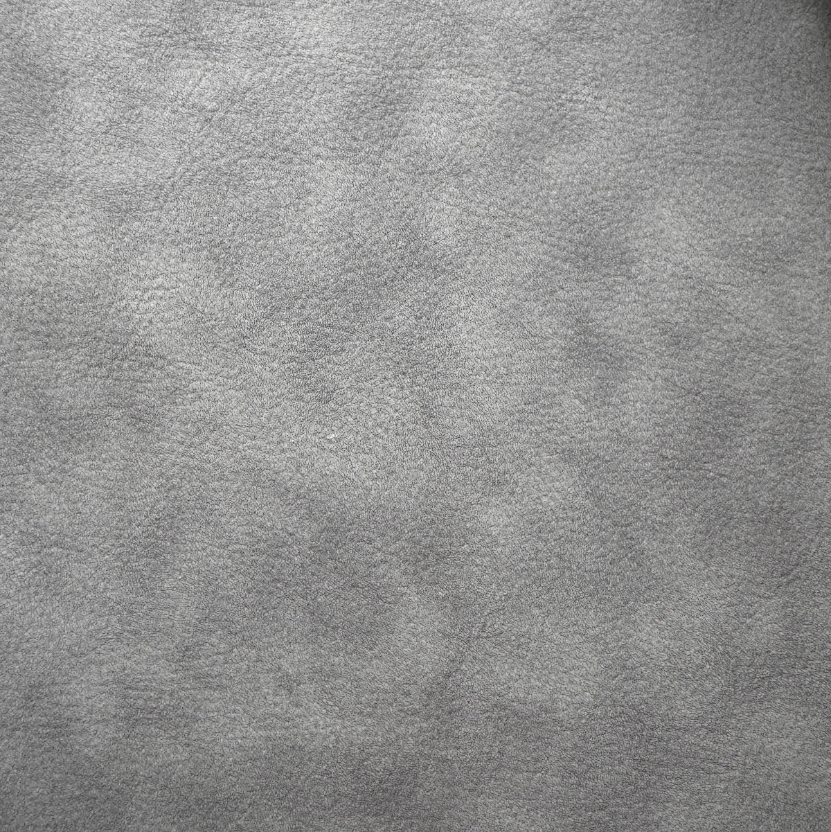 A close-up of a textured gray faux leather or vinyl material surface with a fine grain pattern.